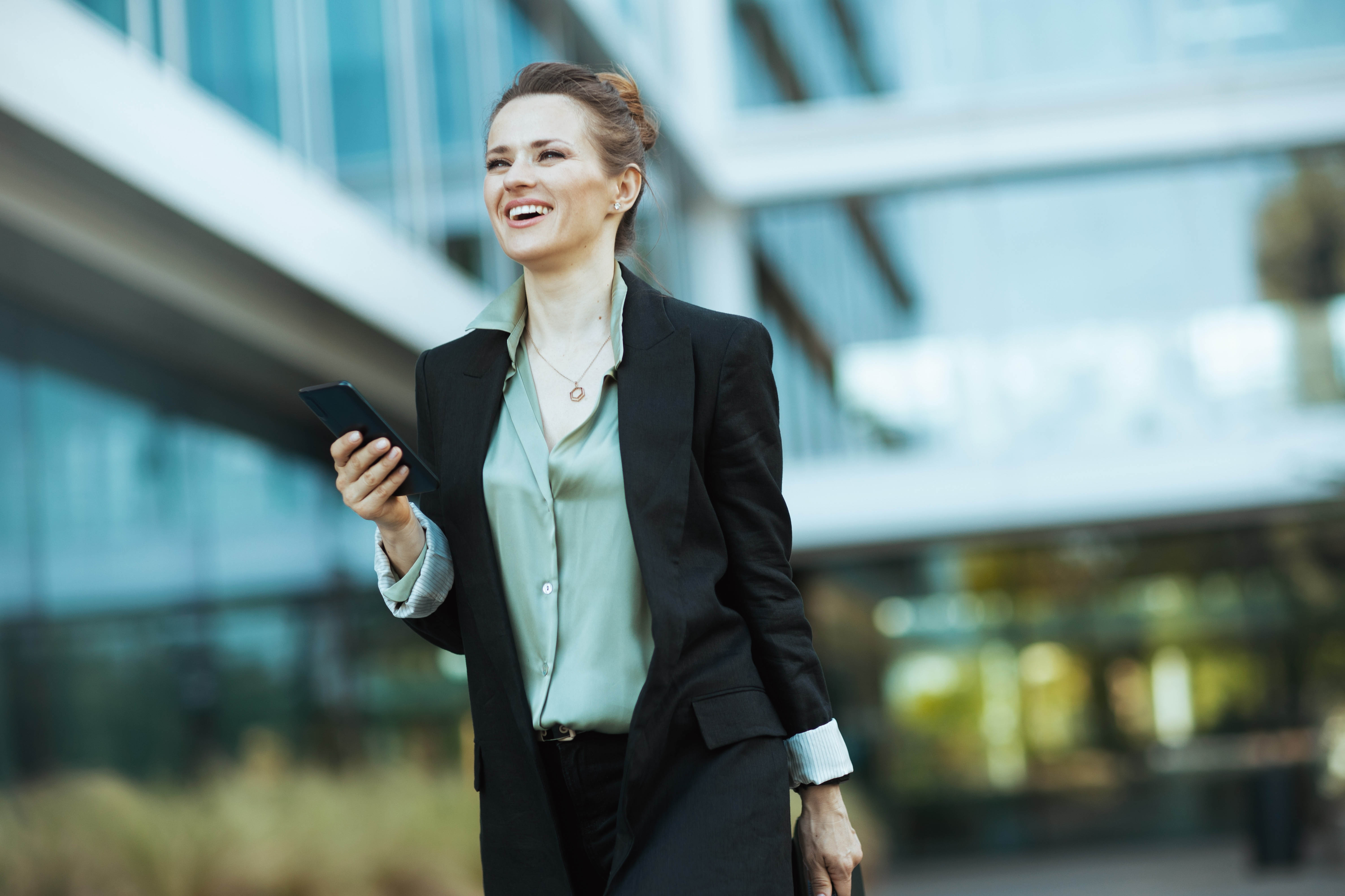 Business woman taking a walk outside with her phone during the work day Business woman taking a walk outside with her phone during the work day